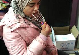 A young woman provides a DNA sample via cheek swab. She was among a cohort of Syrian adolescents forcibly displaced by conflict to participate in a study on the effects of genetic and resilience on the mental health recovery. (Photo courtesy of the research team.)